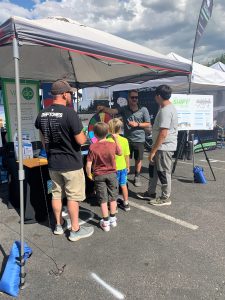 Photo of NFRMPO outreach booth with MPO Staff talking to four people